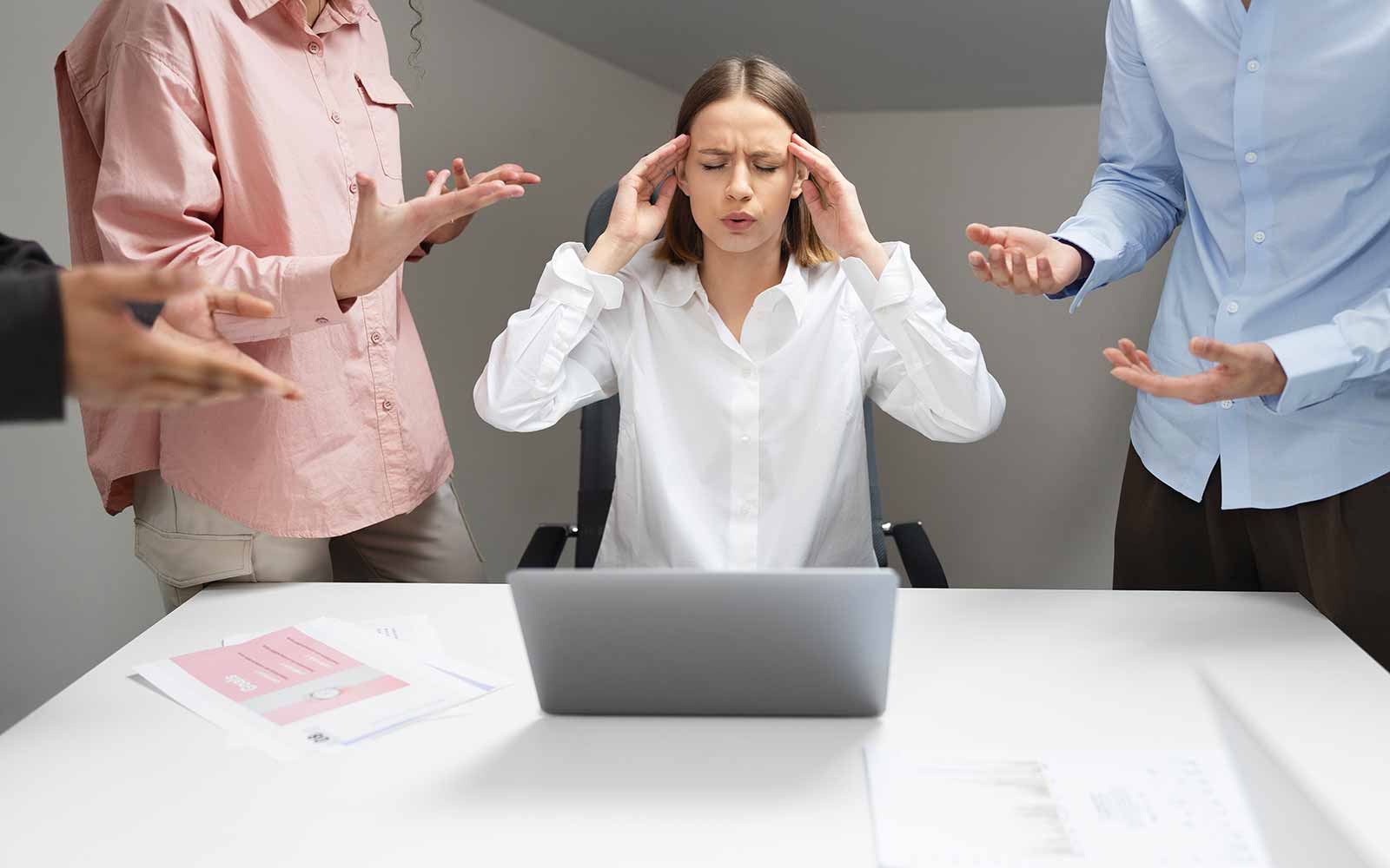 Lavoratrice sotto pressione alla scrivania tra colleghi che discutono – counseling aziendale